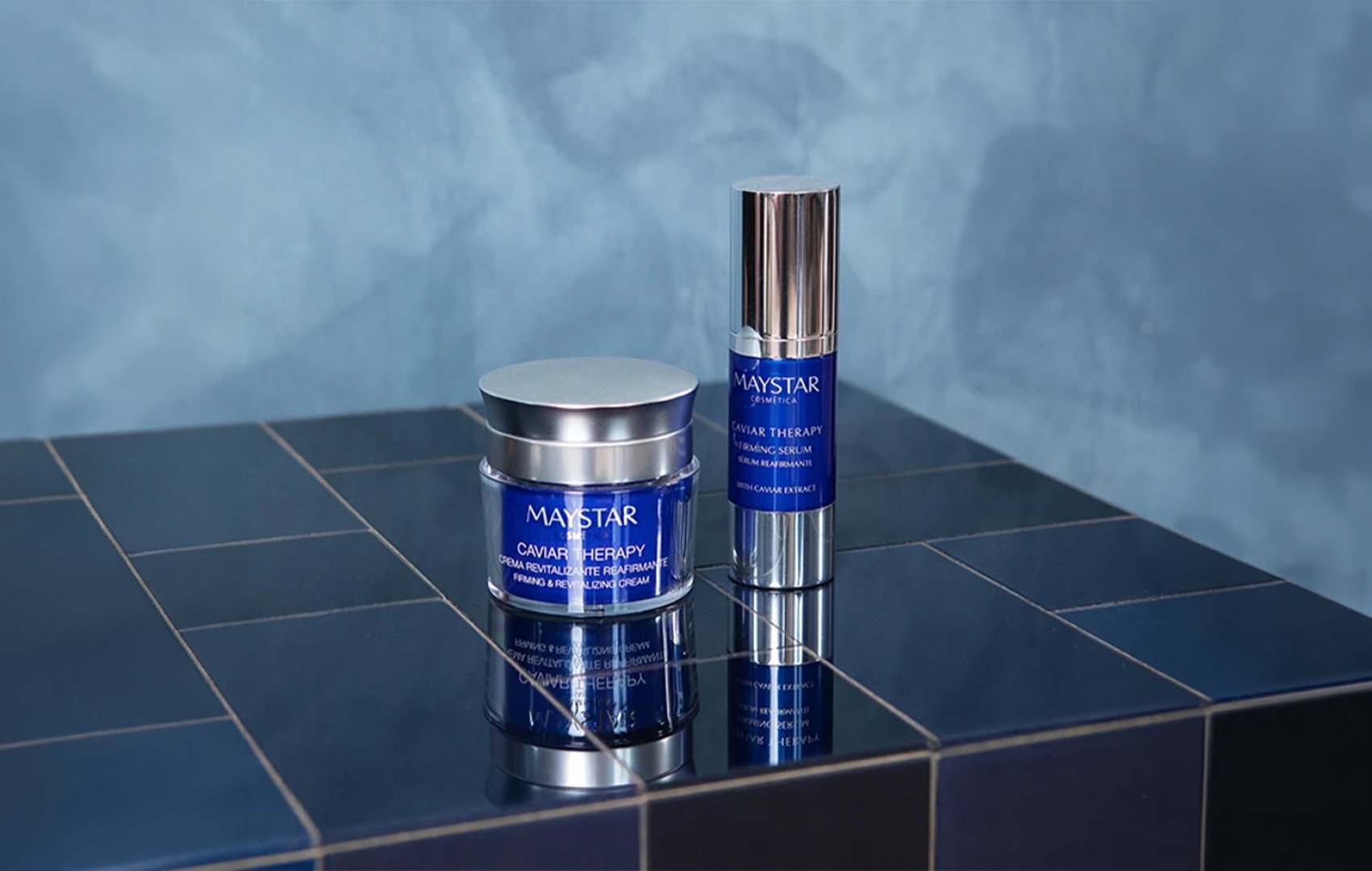 Zwei Kosmetikbehälter der Maystar Caviar Therapy Linie auf einer Fläche aus blauen Fliesen mit hellblauem Hintergrund